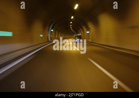 Small car passing through motorway tunnel. Long exposure motion blur. Stock Photo