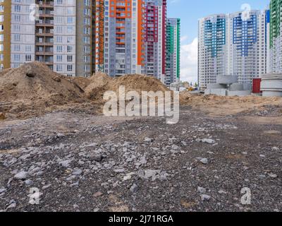 A building site with heaps of sand, concrete rings in the foreground and new colorful high-rise buildings and construction equipment in the background Stock Photo