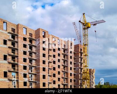 Residential brick house under construction. Unfinished house and tower crane. New multi-storey building Stock Photo