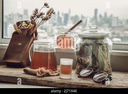 Refreshing with Chinese herbal tea (Jub Lieng) served with honey on old wooden table with city view. Herbal plant and healthy drinks concept, Selectiv Stock Photo