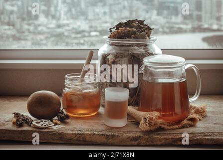 Refreshing with Chinese herbal tea (Jub Lieng) served with honey on old wooden table with city view. Herbal plant and healthy drinks concept, Selectiv Stock Photo