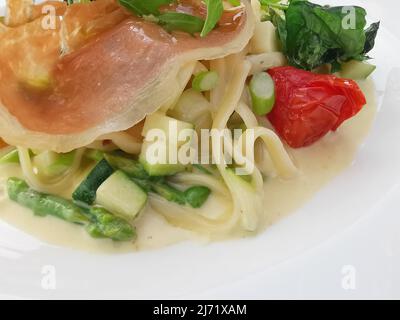 Gourmet pasta dish with parma ham, cheese sauce and vegetables Stock Photo