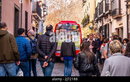 Red bus n 32 riding through the narrow pedestrian street in central Granada, Andalucia, Spain Stock Photo
