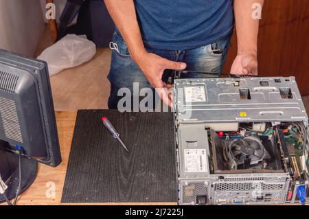 electronics technician man, at home opening computer case, working on maintenance, technical service and repair. Stock Photo