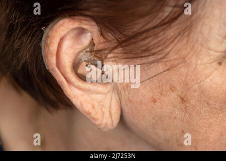 Hearing aid device in senior woman ear - closeup photo Stock Photo