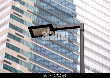 LED street lamp post on skyscraper background. Modern led lights in city, saving of electrical energy Stock Photo