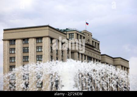 Russian flag on the parliament building in Moscow, view through the fountain splashes. Facade of State Duma of Russia, russian authority Stock Photo