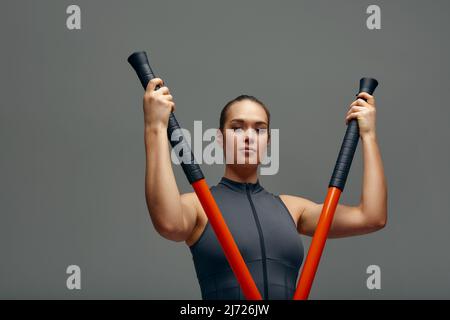 beautiful girl in sports uniform is training kung fu in the studio, fighter athlete, practicing martial arts with a stick Stock Photo