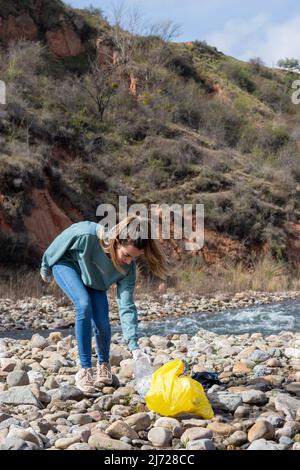 Woman picking up trash and seeing the disastrous and sad near future of the planet earth Stock Photo