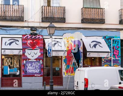 A street artist spraying fresh mural staying on a ladder at Donde da la vuelta el viento restaurant wall, Lavapiez, Madrid, Spain Stock Photo