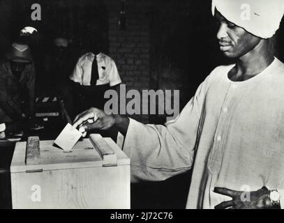 The House Of Representatives Electoral Rules, 1953 '...After recording his vote... the voter shall fold the ballot paper in such a way that the mark he has made on it cannot be seen but the mark of authentication on the back can be seen. The voter shall shew the mark of authentication to the person in charge of the ballot box and shall drop the paper into the ballot box through the aperture...' November 10, 1954. Stock Photo