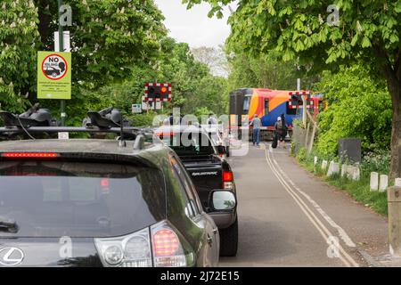 Stationary cars queuing and idling as a South Western Railway train passes Network Rail's Vine Road signal box in Barnes, London, SW13, England, UK
