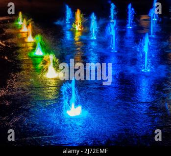 Colourful illuminated waterspout fountain at night Stock Photo