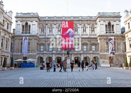 Exterior view of Royal Academy of Art building, British painter Francis Bacon banner and people in the courtyard April 2022 London UK KATHY DEWITT Stock Photo