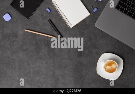 Workspace top view with laptop, notepad, pens and coffee on dark grey stone background. Flat lay with copy space. Business concept. Stock Photo