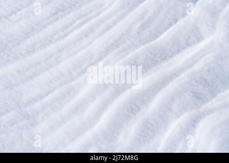 Freshly fallen snow surface looking like dunes shaped by wind. Winter abstract snow texture background. Stock Photo