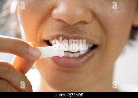 Woman Using Nicotine Gum To Quit Smoking. Nicotine Replacement Therapy Stock Photo