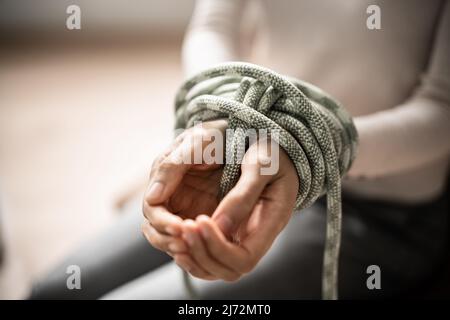 Slavery Victim And Hostage Tied By Rope. Violence And Crime Stock Photo