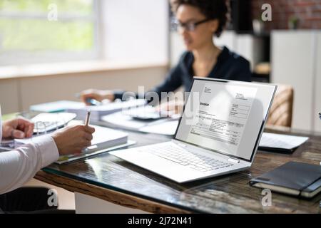 Elevated View Of Two Businesspeople Calculating Invoice With Calculator At Workplace Stock Photo