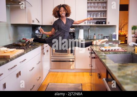 Female ballet dancer cooking in a residential kitchen Stock Photo