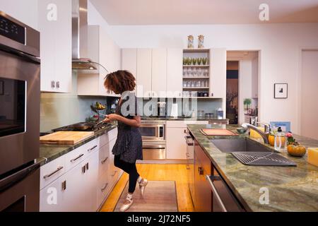 Female ballet dancer cooking in a residential kitchen Stock Photo