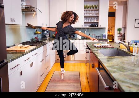 Ballet dancer reaching for eggs while cooking breakfast in kitchen Stock Photo