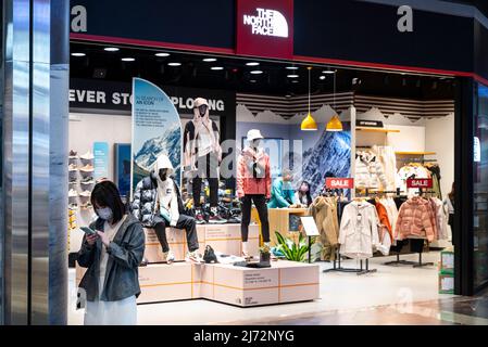 A shopper stands next to the American outdoor clothing brand, The North Face store, in Hong Kong. Stock Photo