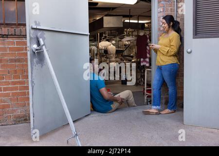 Young man and woman in back room of dry cleaners taking a break between customers Stock Photo