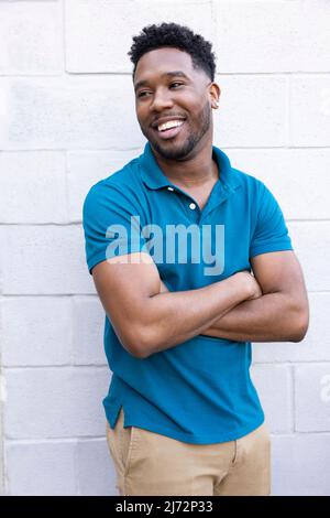 Confident young Black man in blue polo shirt looking off camera smiling. Stock Photo