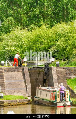 Canal narrowboat passing through locks on the Trent and Mersey canal as it passes through the village of Wheelock Cheshire England Stock Photo