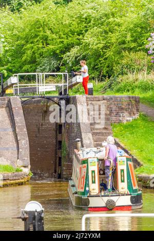 Canal narrowboat passing through locks on the Trent and Mersey canal as it passes through the village of Wheelock Cheshire England Stock Photo