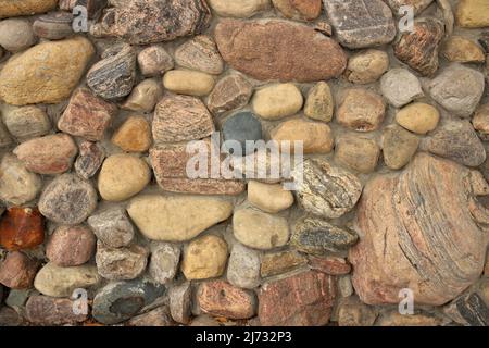 Close up of A stone Wall Built with Multi Colored Rocks and Cement Mortar. Background texture Stock Photo