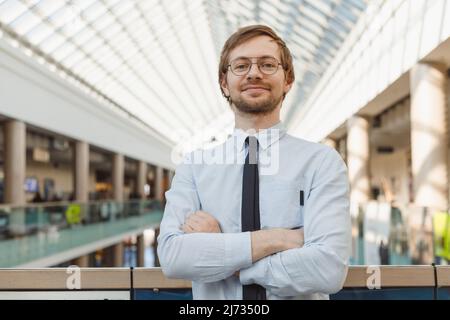 Portrait of handsome cheerful intelligent man in glasses over modern building background Stock Photo