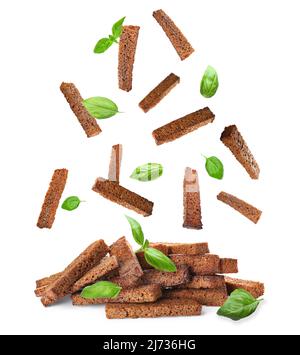 Falling rye croutons with green basil leaves on white background Stock Photo
