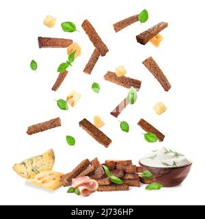 Falling rye croutons with cheese, basil leaves and sour cream on white background Stock Photo