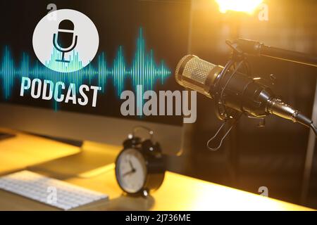 Stand with professional microphone near workplace with computer in dark room Stock Photo