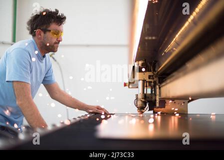 Within heavy industry. A man works in a modern factory on a CNC machine. Selective focus Stock Photo
