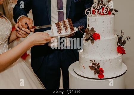 groom and bride at wedding cut their large multi-tiered white cake taste it fed from each other. Slavic Ukrainian Russian traditions Stock Photo