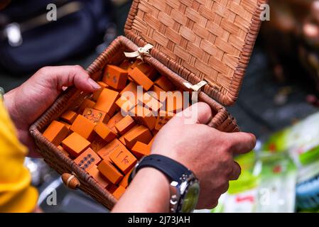 A man in the market holds a box of traditional Chinese mahjong made of bamboo Stock Photo