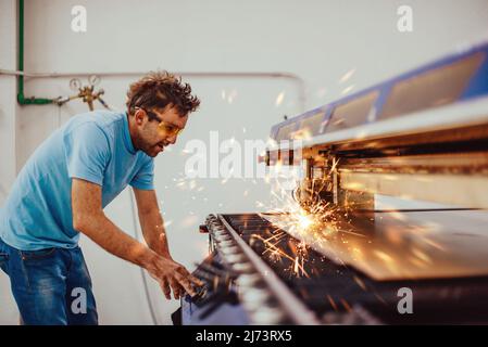 Within heavy industry. A man works in a modern factory on a CNC machine. Selective focus Stock Photo