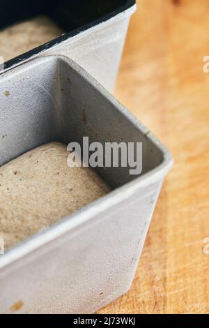 The process of making rye bread. The dough on the rye bread is laid out in a mold. Vertical photo. Stock Photo