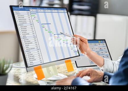 Young Businesspeople Analyzing Gantt Chart And Calendar On Computer In Office Stock Photo