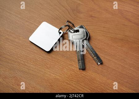 Two house keys and keychain on wooden background. Stock Photo