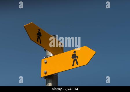 Two yellow signposts with walking figures and arrows point in different directions Stock Photo