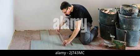 Bricklayer measuring tiles to install a floor Stock Photo