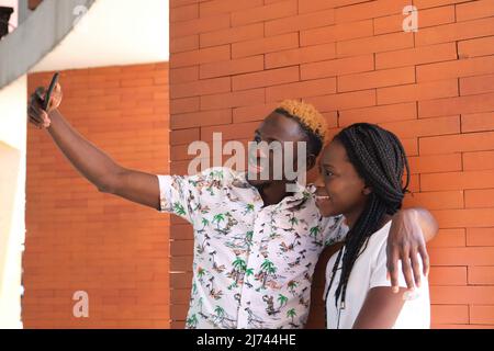 Young african happy couple taking a selfie with their smartphone. Stock Photo