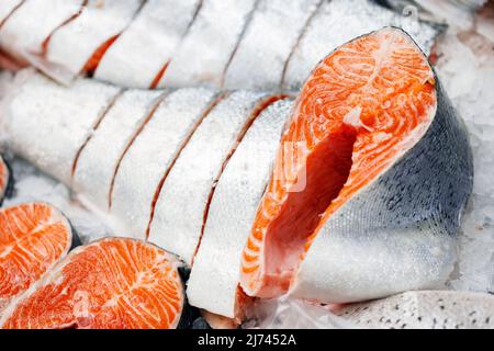 Trout, cut into pieces, laid out on ice on store counter. Pieces of red fish in close-up. Stock Photo