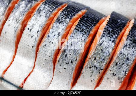 Trout, cut into pieces, laid out on ice on store counter. Pieces of red fish in close-up. Stock Photo