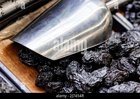 Pile of prunes and kitchen scoop on counter at market Stock Photo