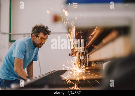 Within heavy industry. A man works in a modern factory on a CNC machine. Selective focus Stock Photo